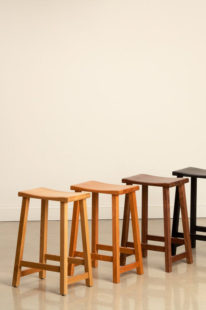 Kenzai counter stools in a rainbow of woods including white oak, cherry, walnut and black