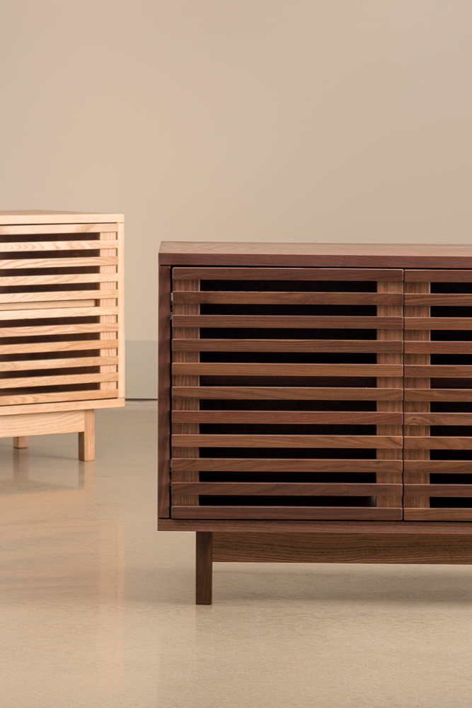 Two small Upland Media Stands from Chilton Furniture in sparse cement room, one in dark walnut wood, the other in light white oak wood