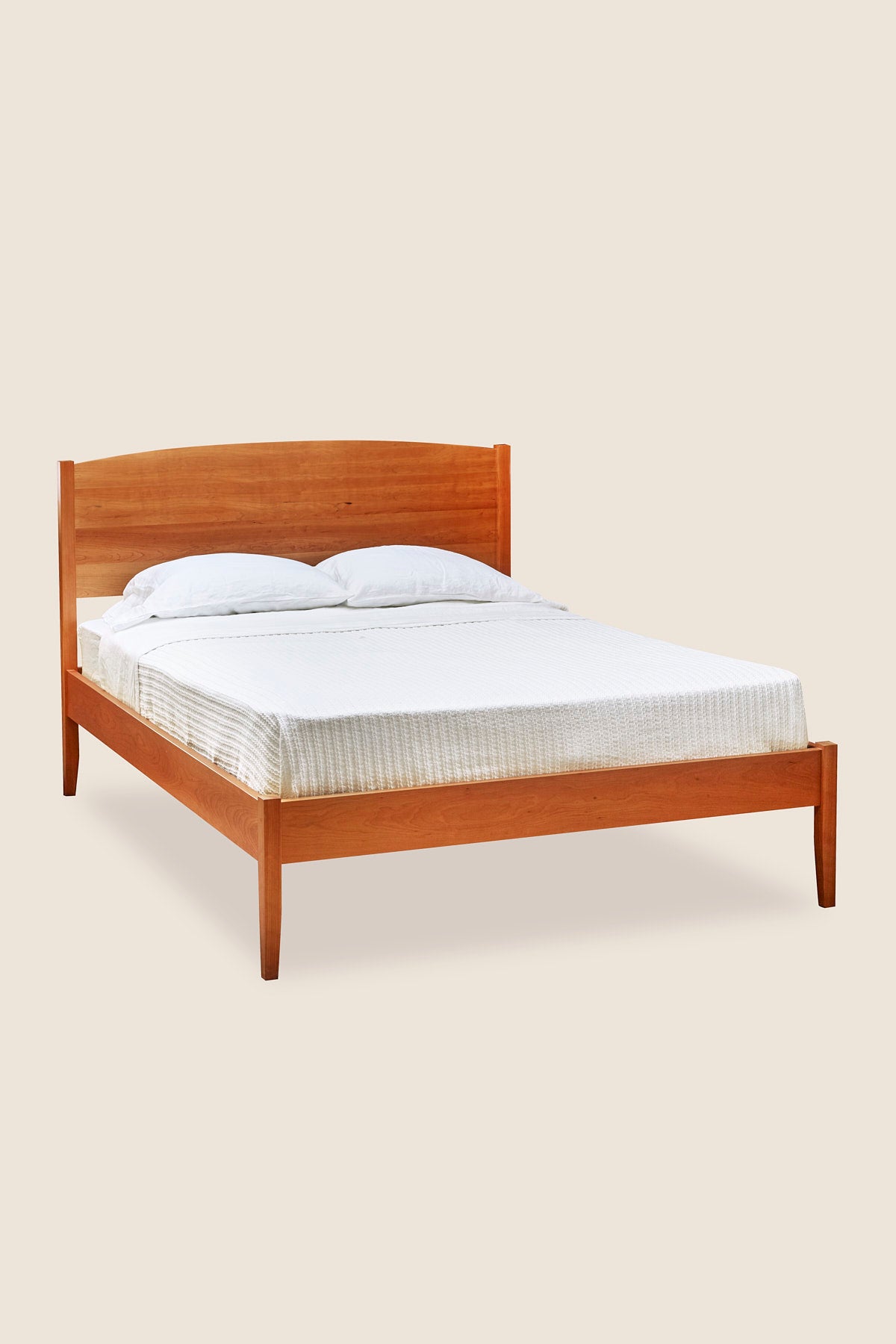 Shaker style, handmade solid cherry wood bed, with arched top and tapered legs, from Maine's Chilton Furniture Co.