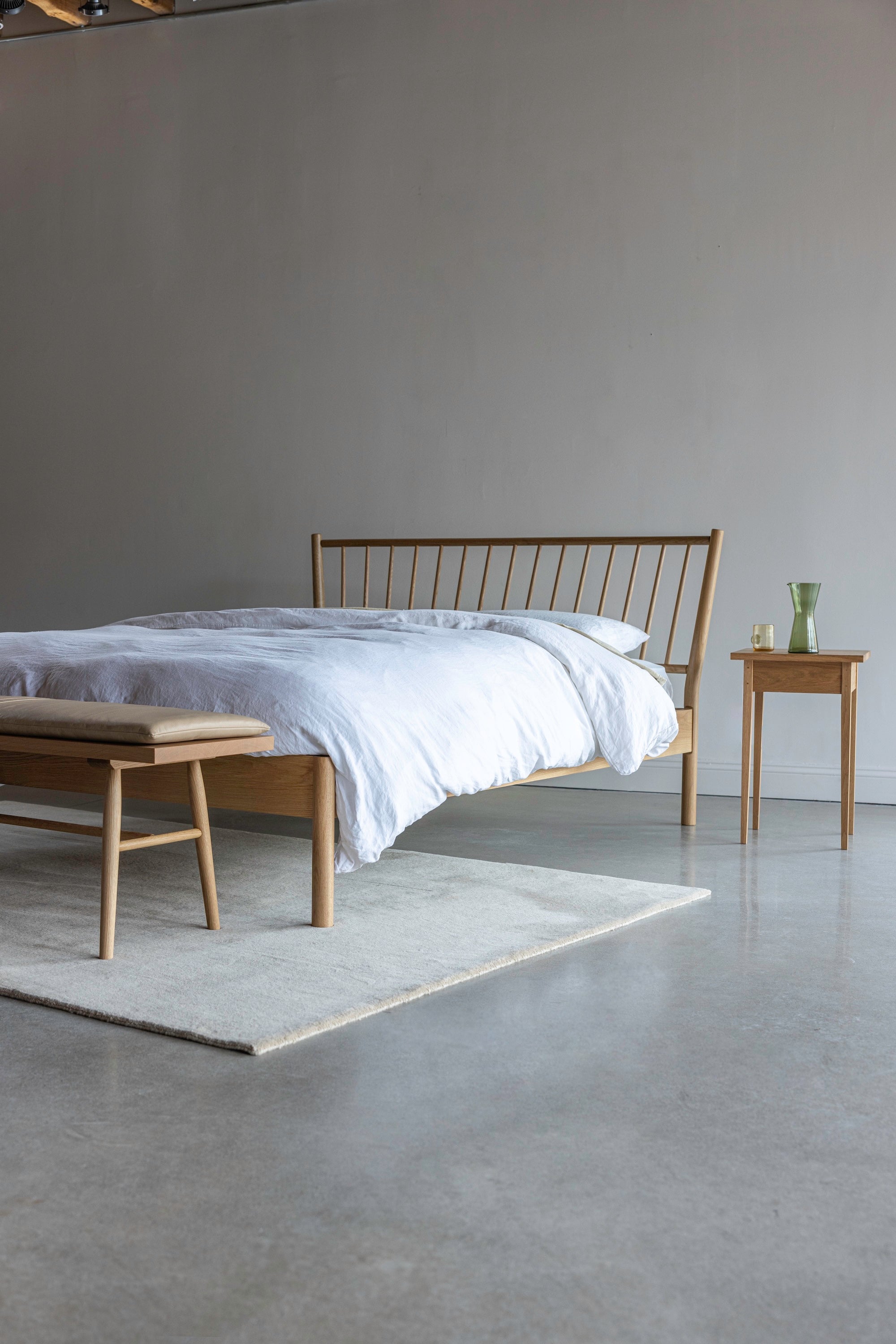 Spindle Chamberlain Bed from Chilton Furniture next to the Heirloom Side Table styled with glass drink ware and the Hudson Bench with Cushion at the foot.