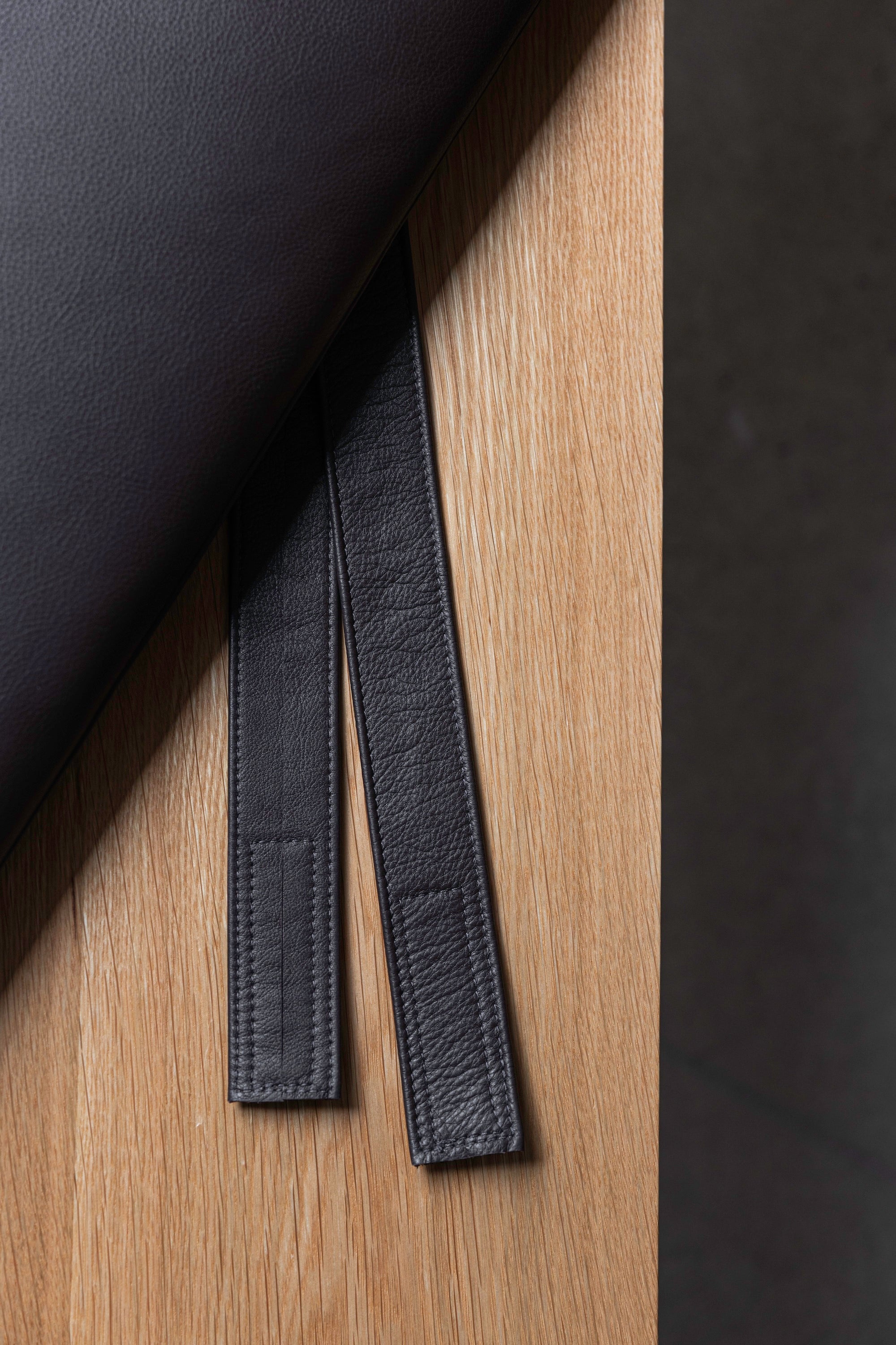 Strap on dark brown leather cushion against white oak wood as part of the Hudson Bench from Chilton Furniture