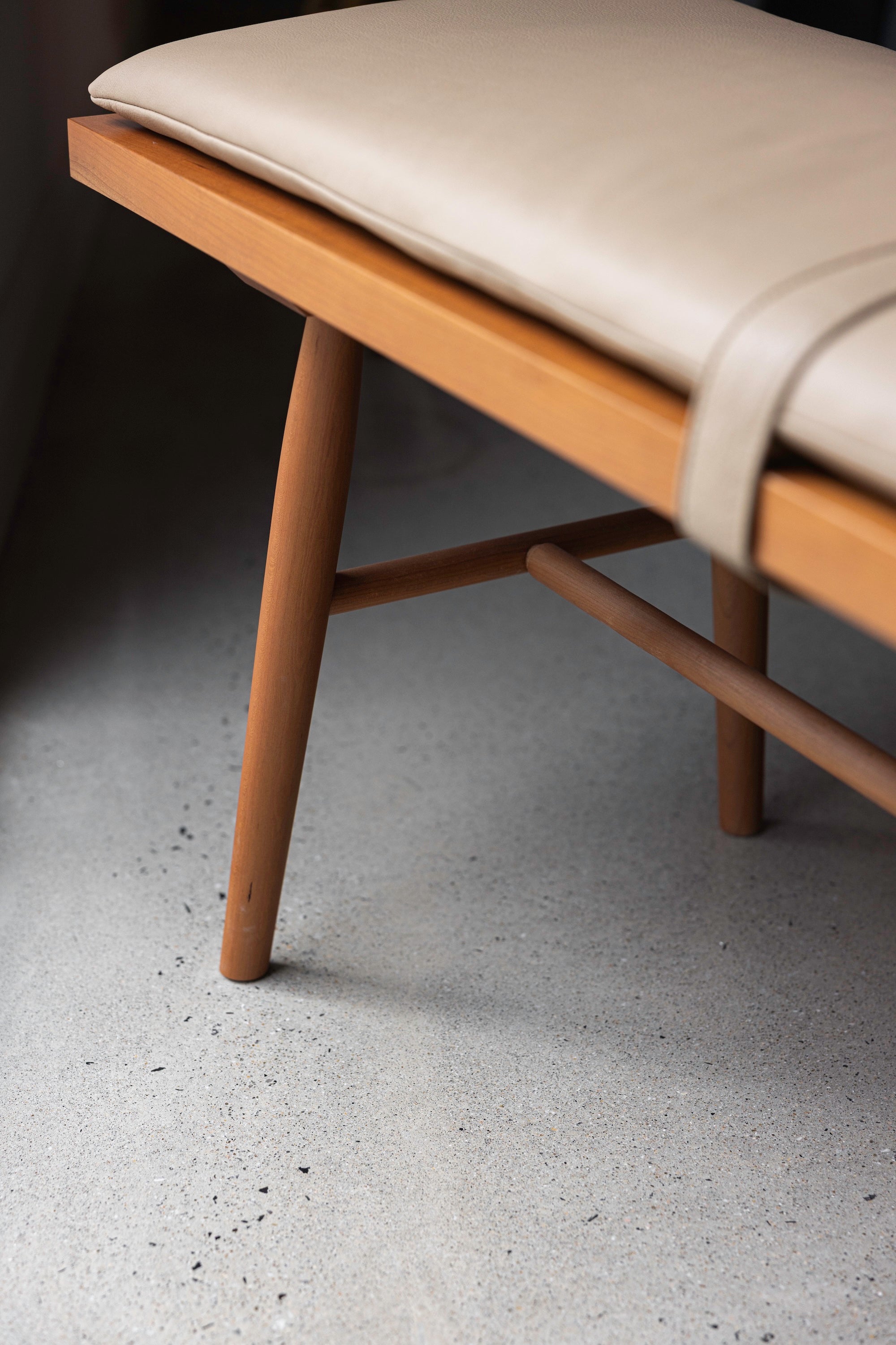 Details of the cherry wood, turned legs and stretchers, and leather cushion on the Hudson Bench from Chilton Furniture