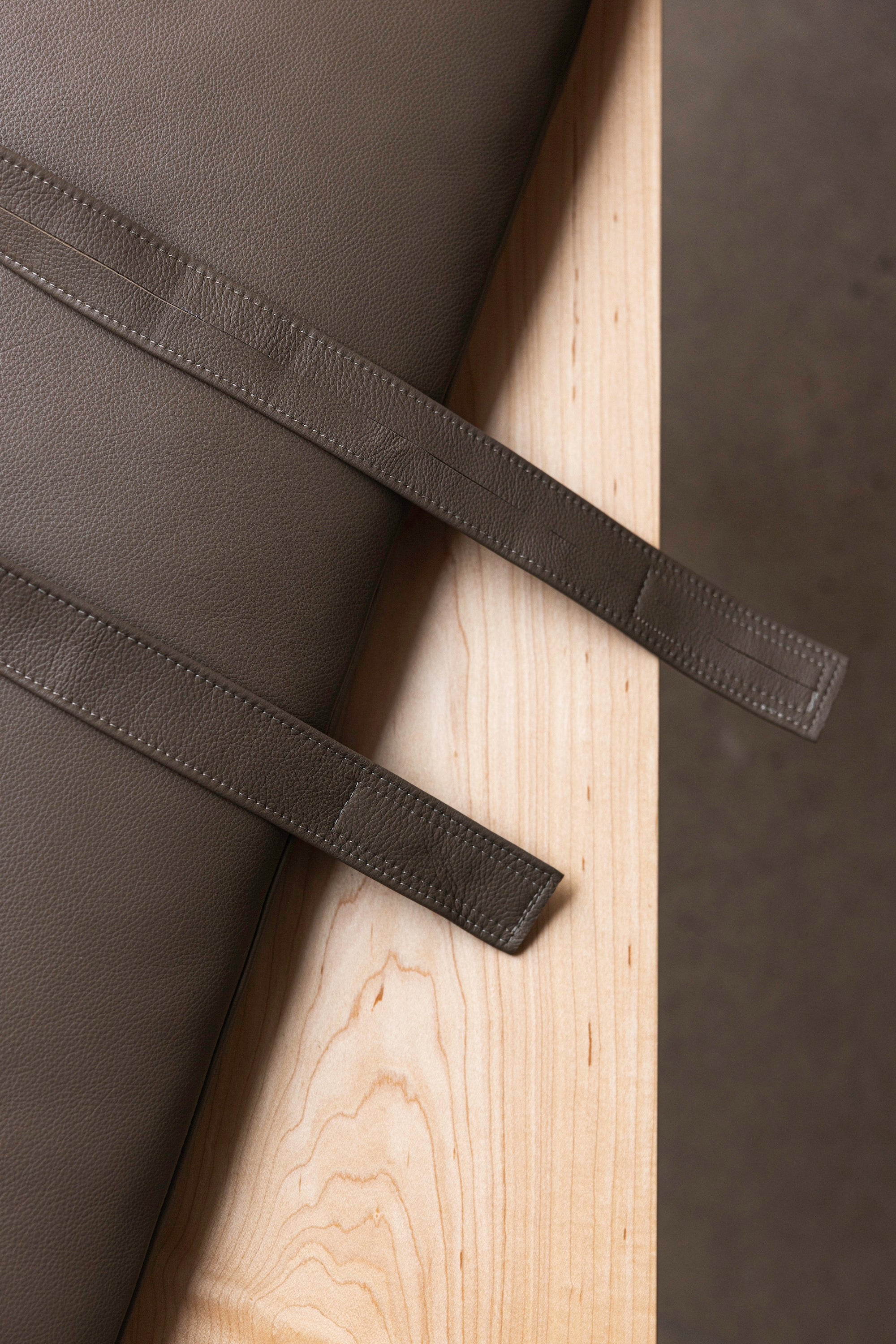 Securing strap and cushion in leather upholstery against maple wood as part of the Hudson Bench from Chilton Furniture