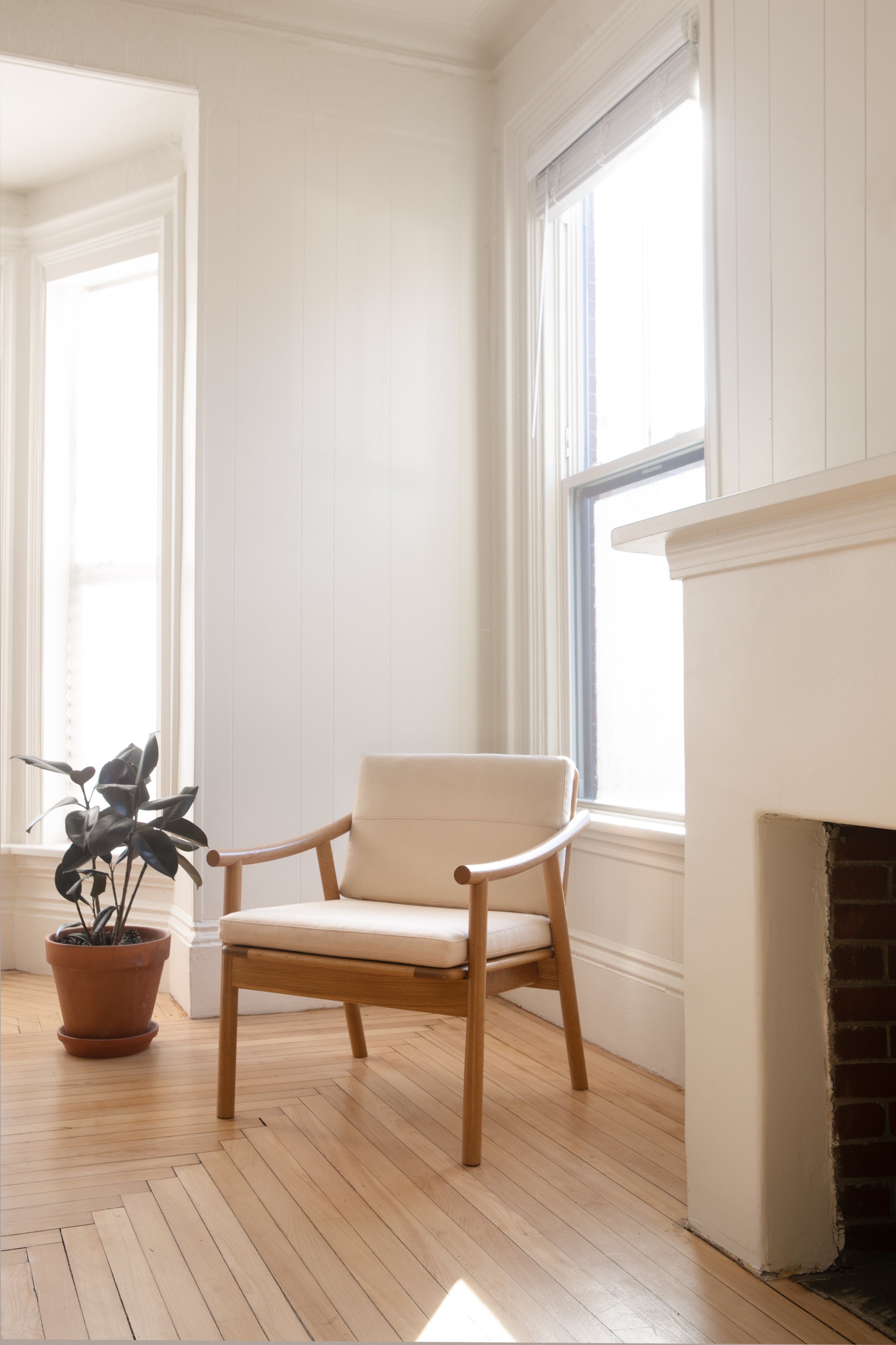 Award winning Nautilus Lounge Chair in bright apartment with wood floors, white fireplace and potted plant.