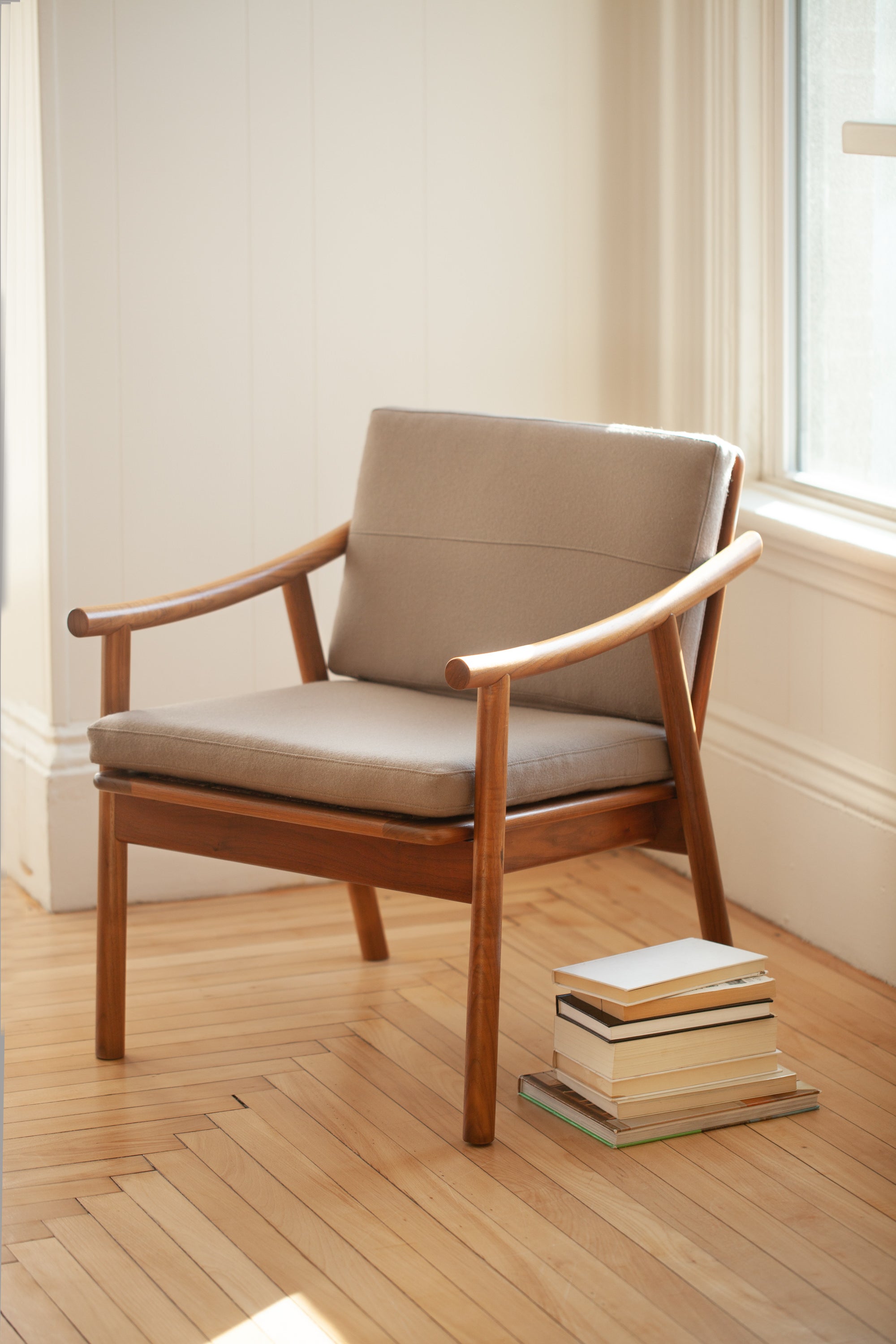 Award winning Nautilus Lounge Chair in bright white apartment with wood floors and a pile of books