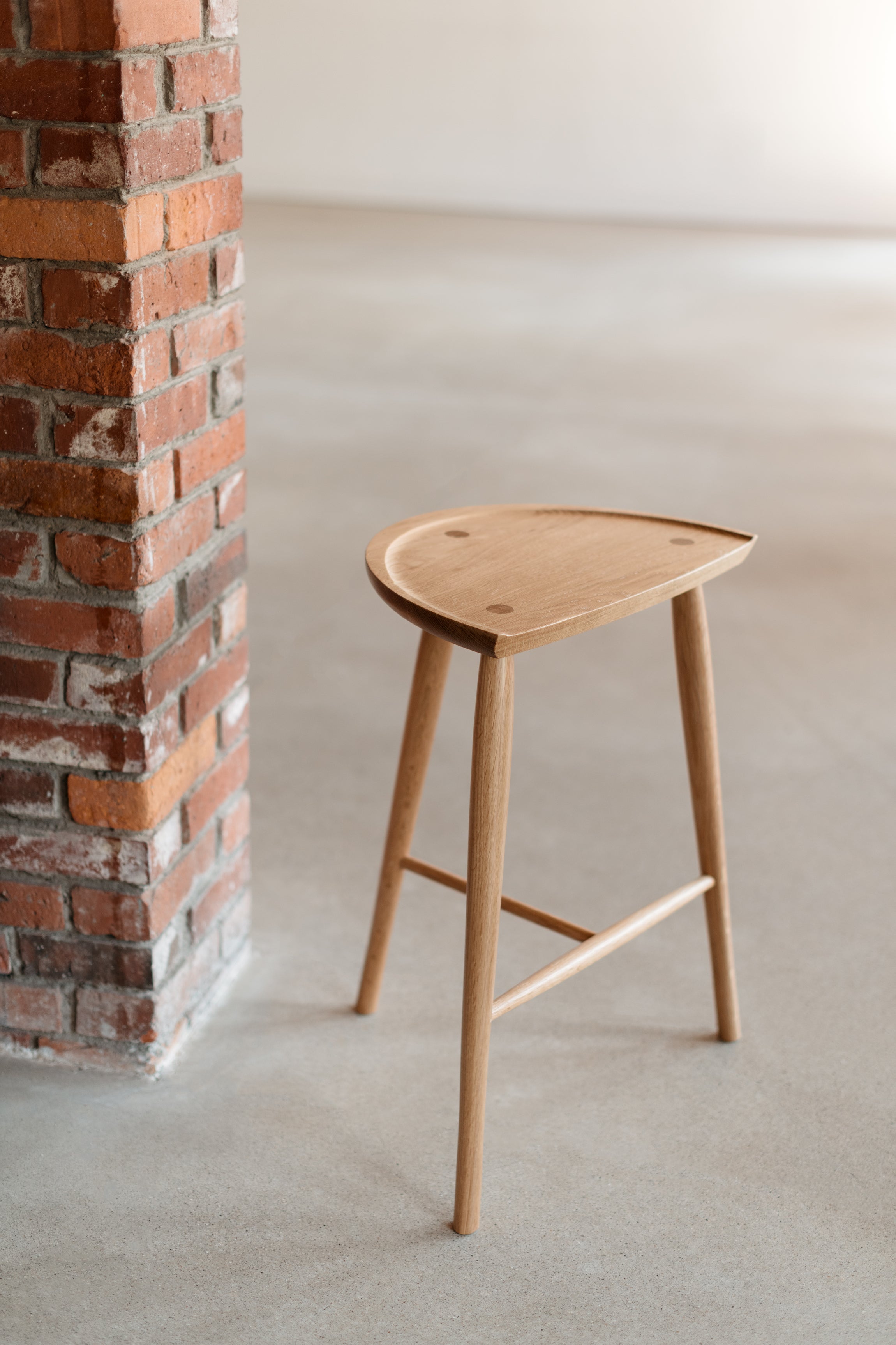 White oak Shaker Stool with three legs in industrial brick room from Chilton Furniture in Maine