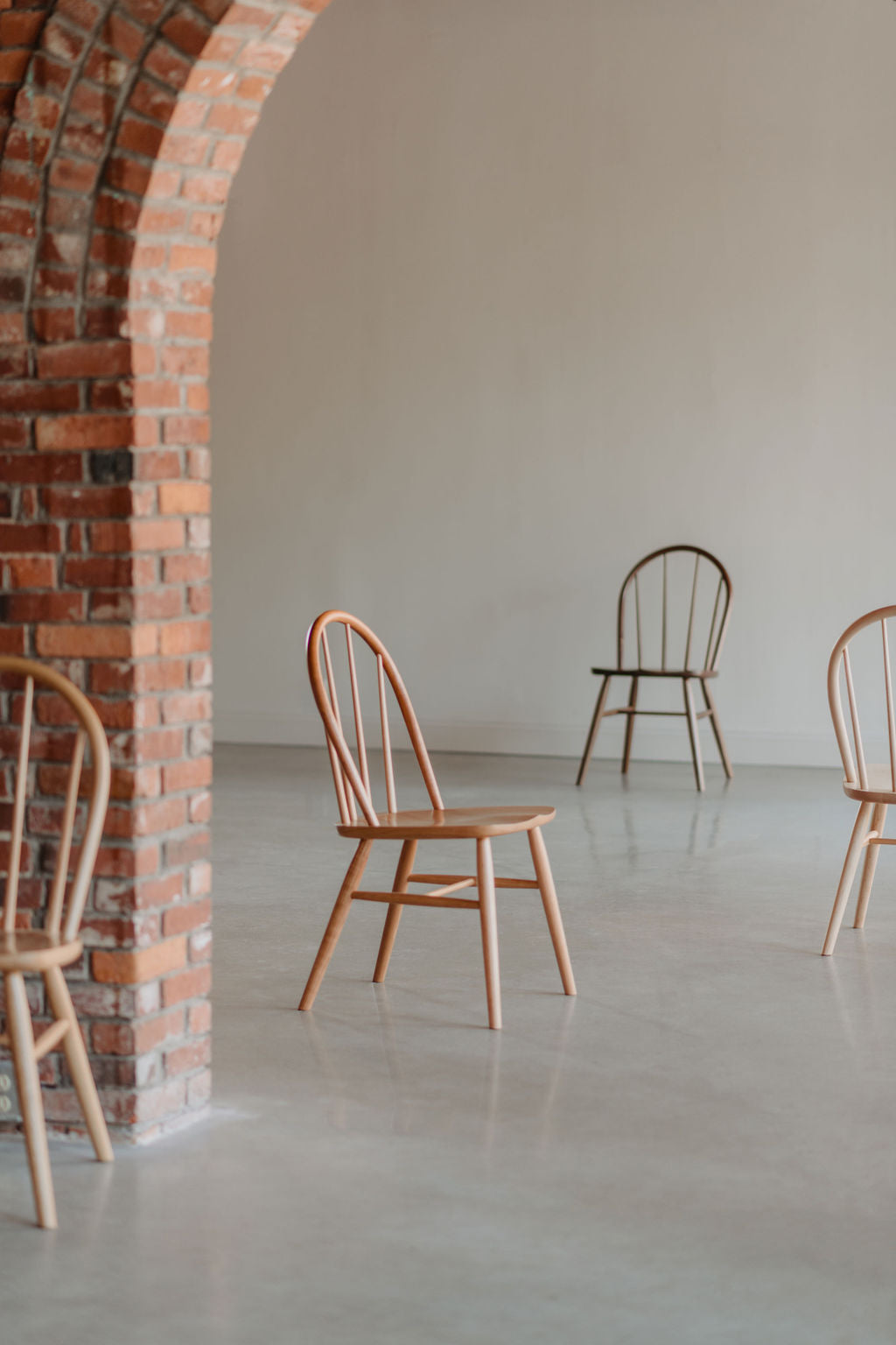 Four bowback chairs at various distances in large room with brick arch