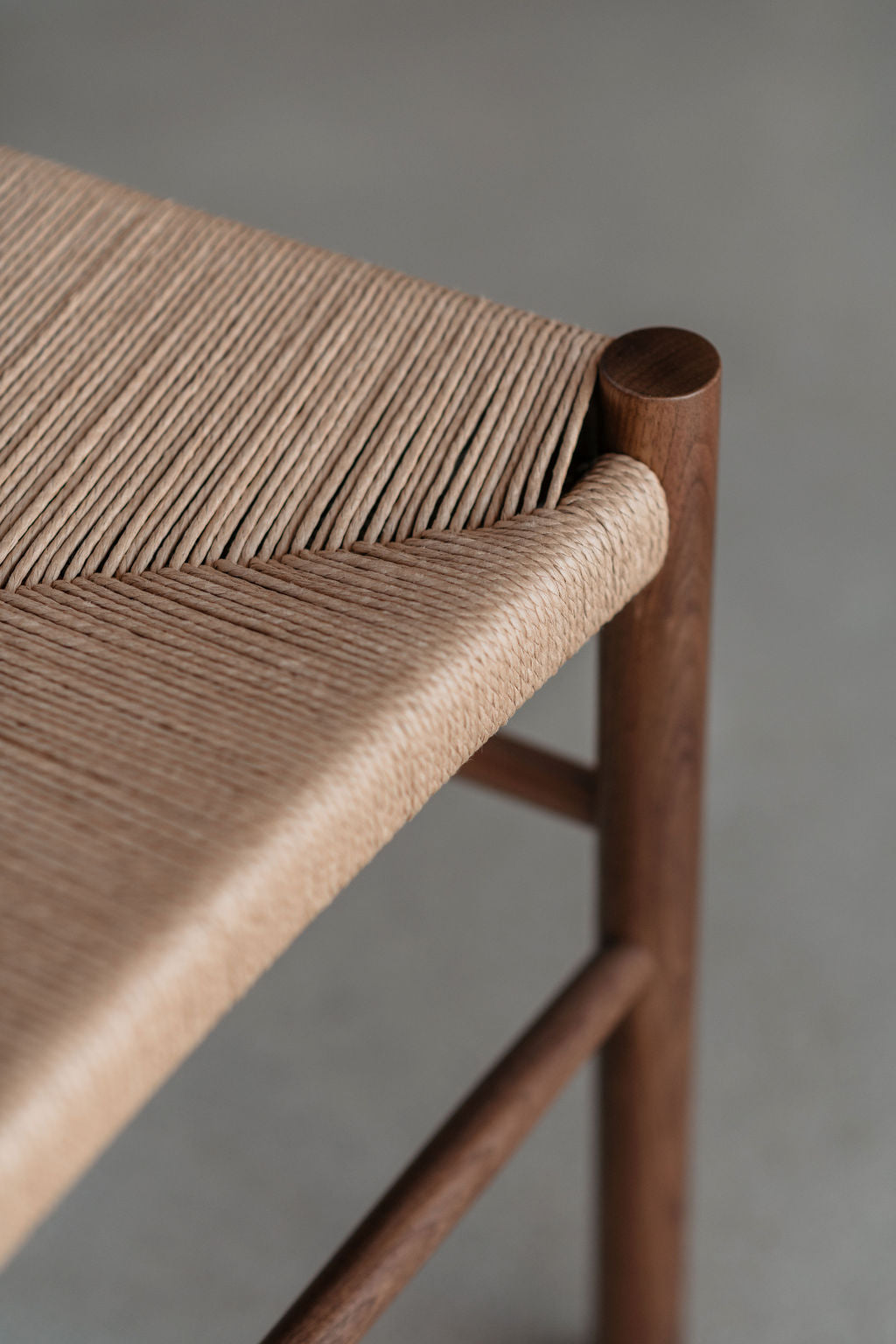 Details of woven danish cord seat meeting cylindrical leg on dining chair