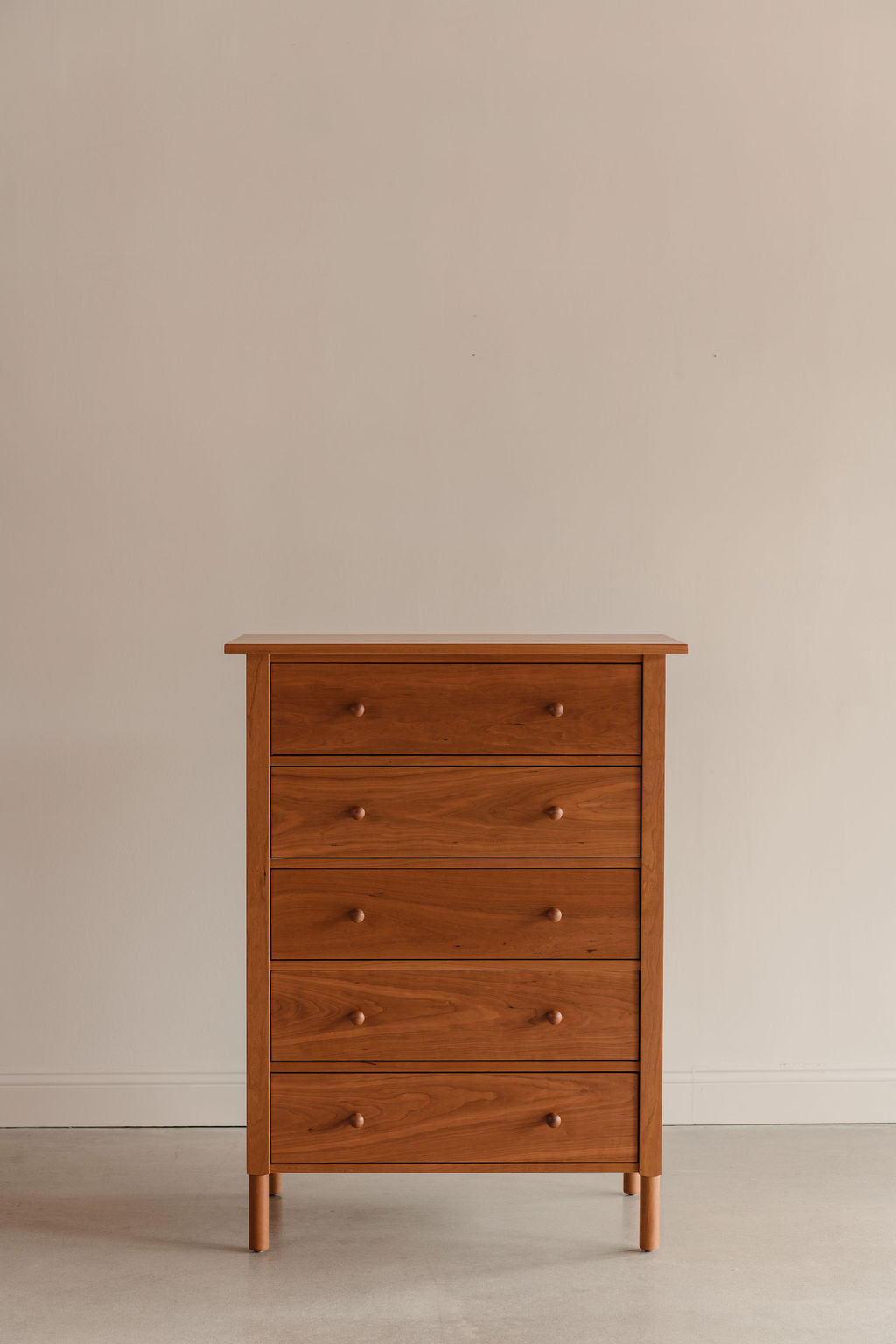 Wooden dresser with five drawers on a beige background