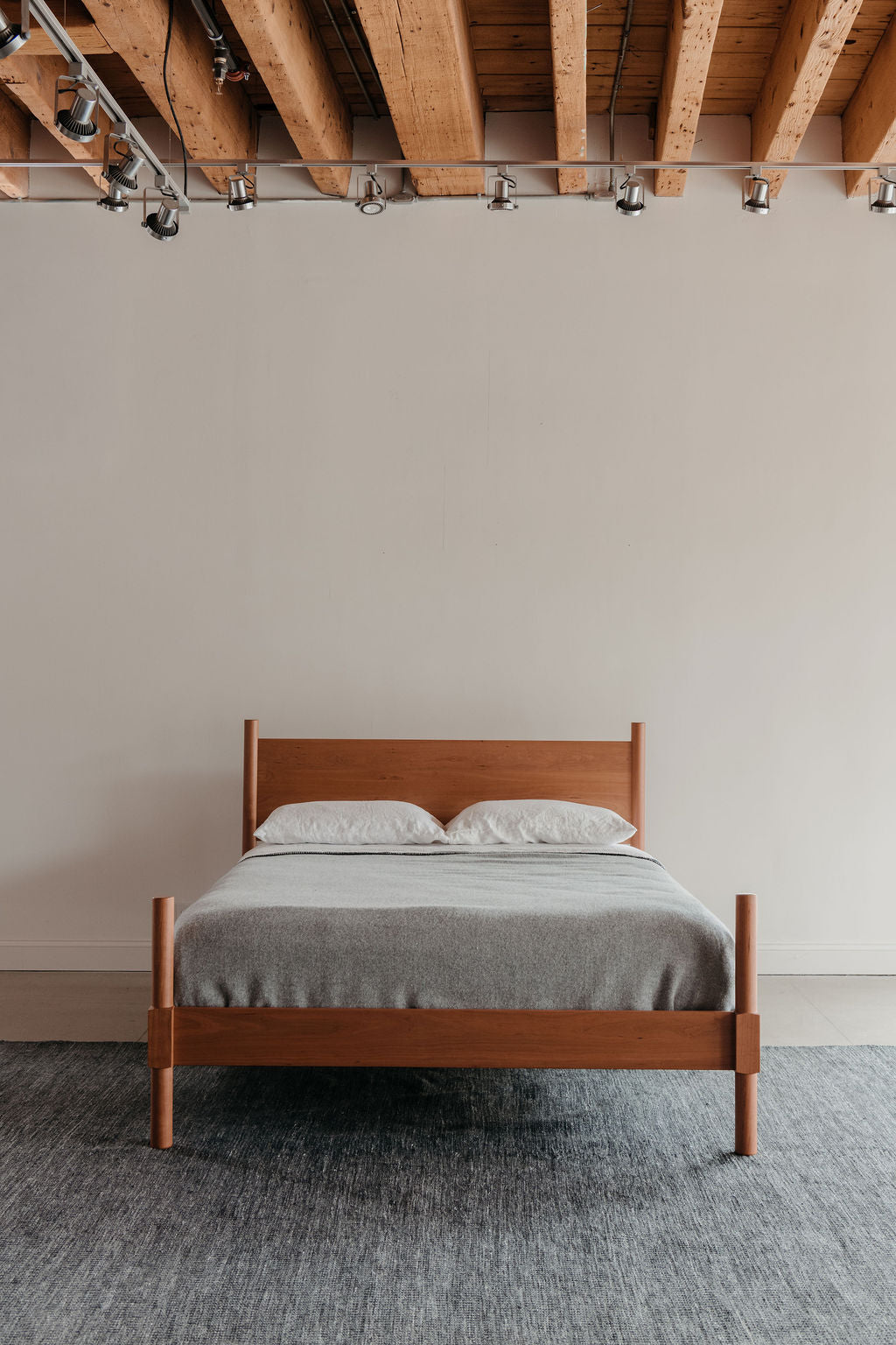 Cherry MS1 Bed with round headboard and footboard posts on traditional Shaker style bed with white pillows and gray blanket