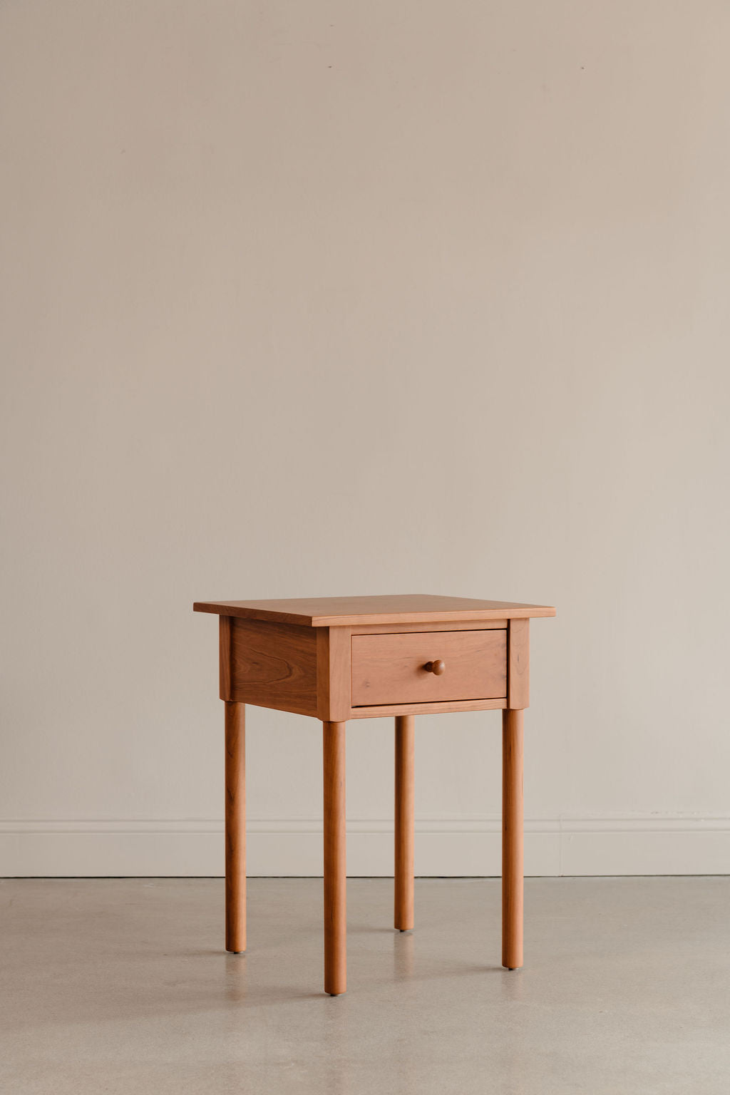 Modern interpretation of a classic Shaker style nightstand with one drawer and rounded legs, in solid cherry wood
