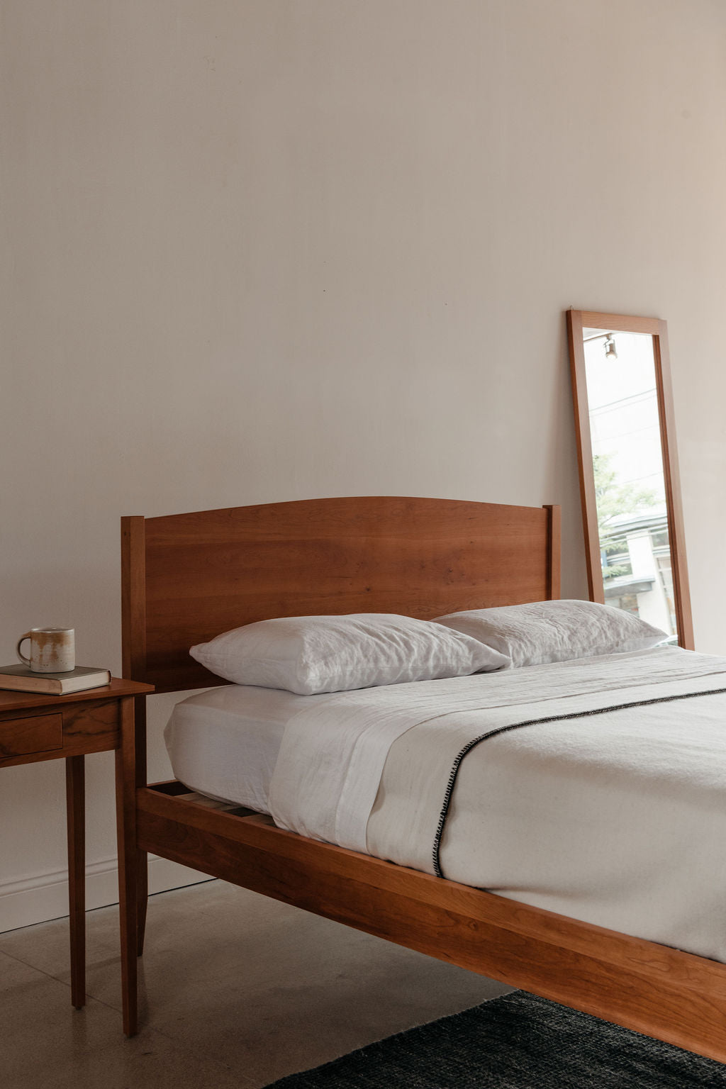 Wooden bed with white bedding in a minimalistic bedroom setting