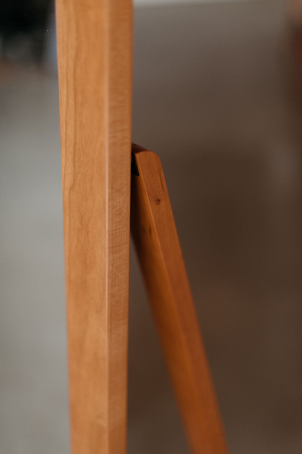 Close-up of a wooden mirror frame with a wooden stand and a blurred background