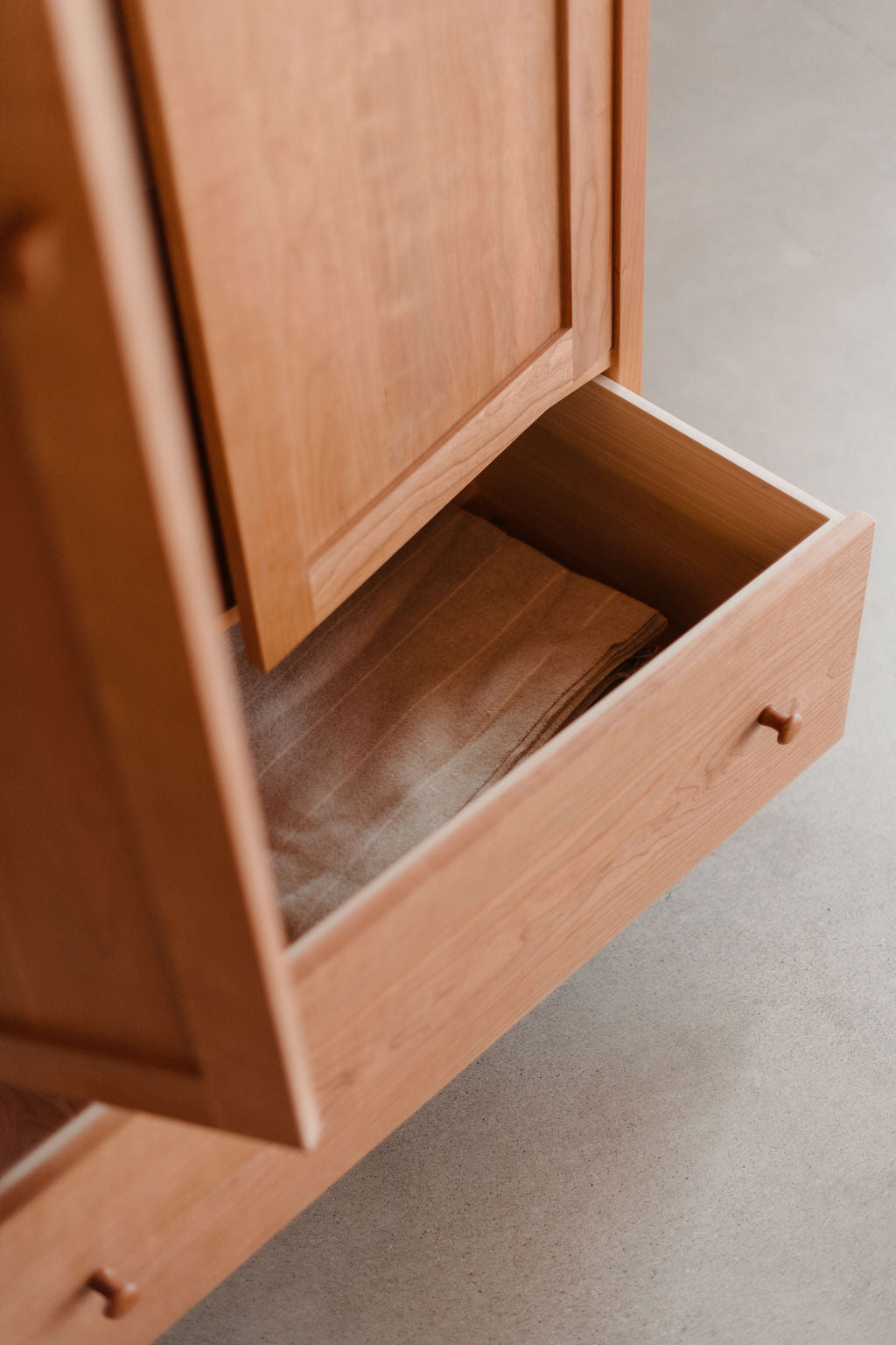 Wooden cabinet with an open drawer on a light gray background