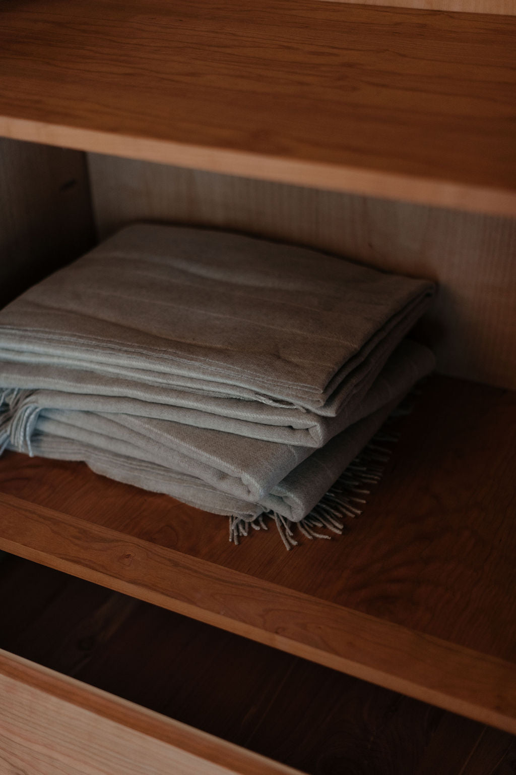 Folded gray blanket on a wooden wardrobe shelf