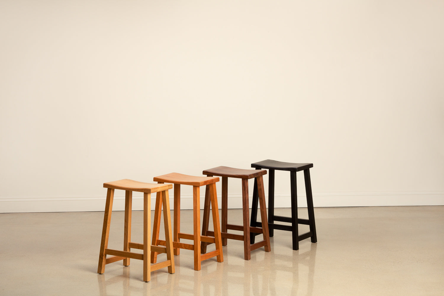Kenzai counter stools in a rainbow of woods including white oak, cherry, walnut and black