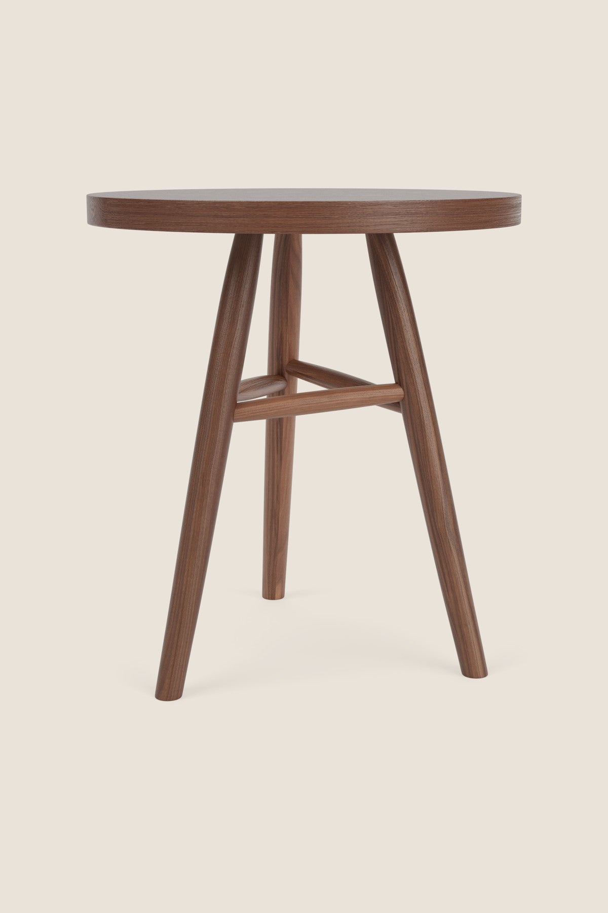 Round wooden Hudson Side Tables with three legs in walnut wood on beige background