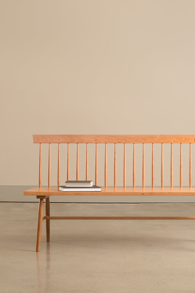 A head on view of an angular version of a traditional spindle back bench with books on the seat