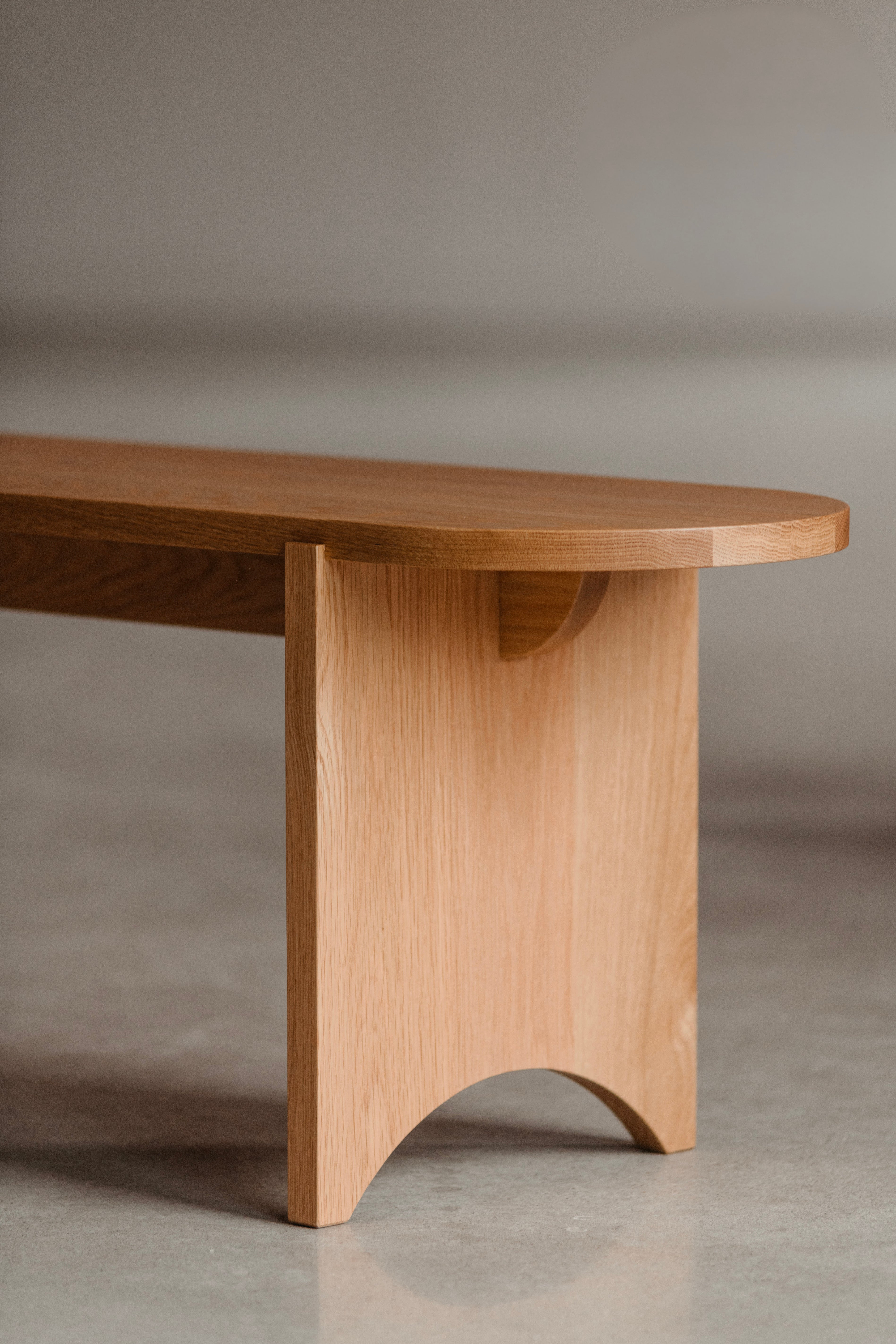 Modern Shaker-inspired bench in white oak with repeated arcs in legs and seat.