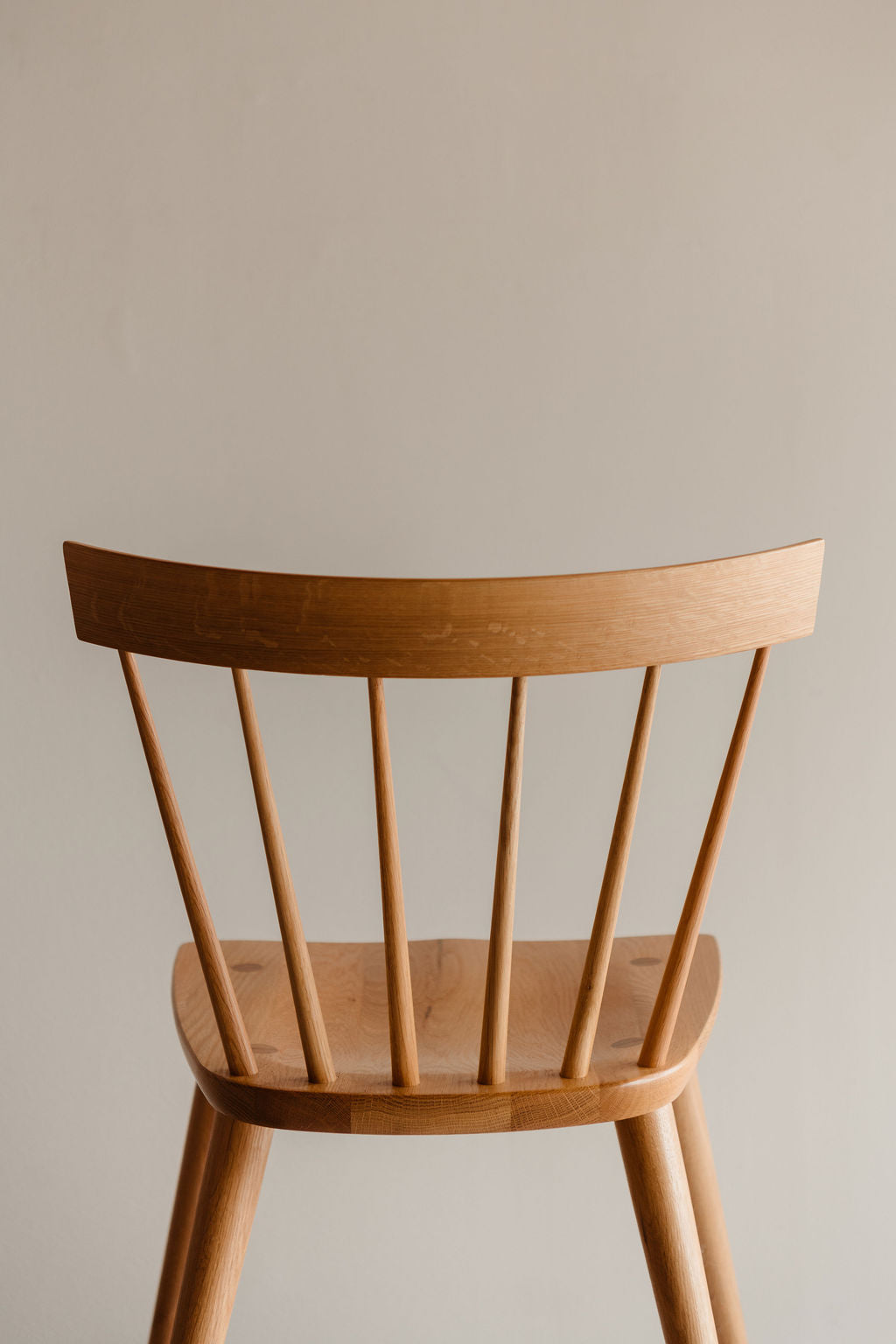 Wooden spindle chair with a curved backrest on a plain background