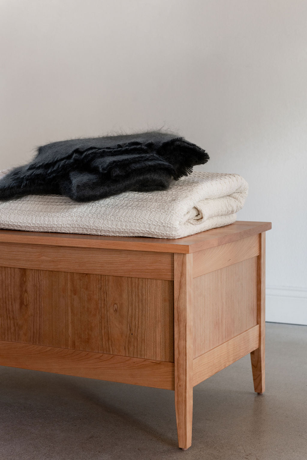 Shaker Blanket Box in cherry wood with white and green blankets on top. 