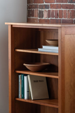 Cherry bookcase in modern home with red brick, styles with books and wooden bowls