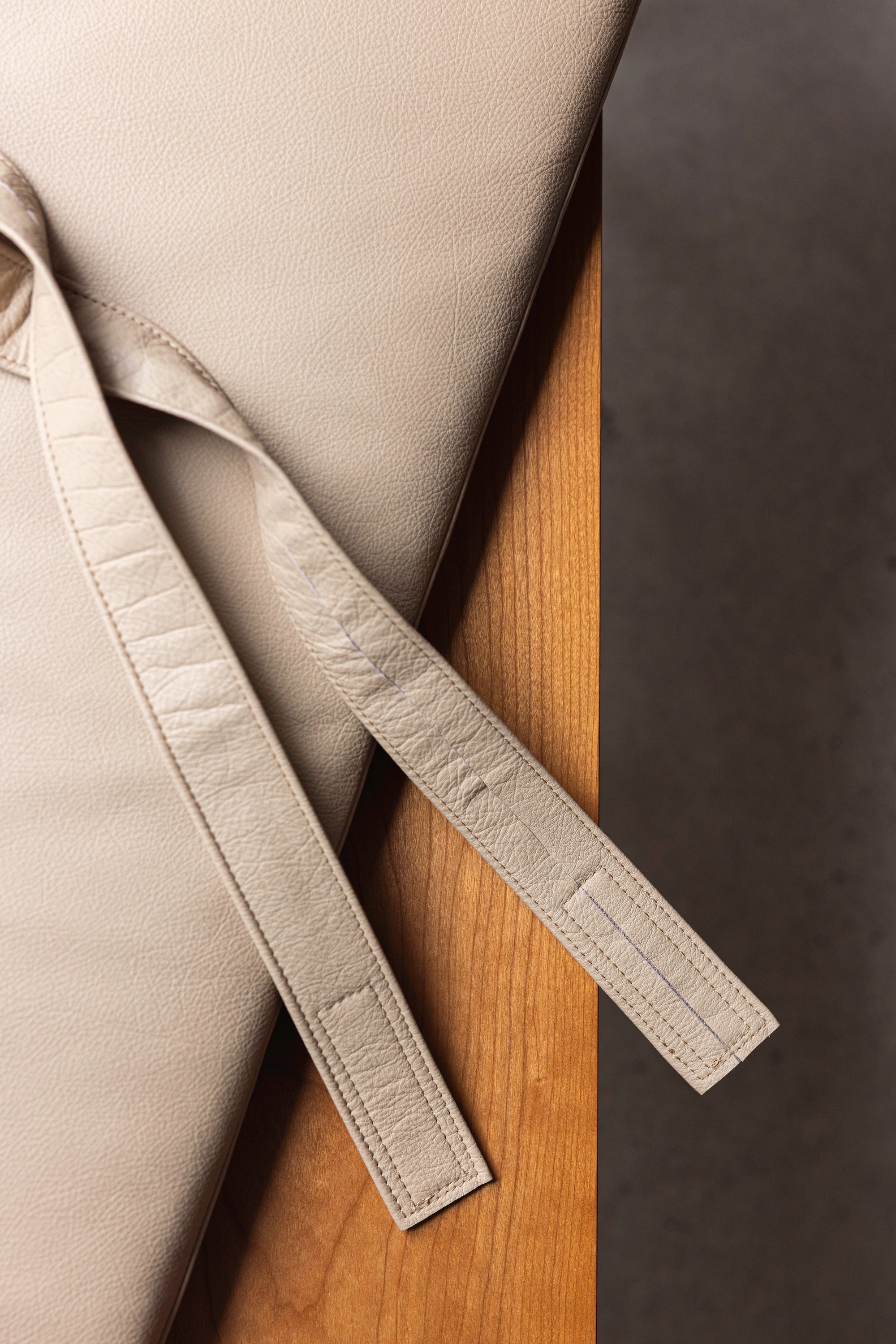 Securing strap and cushion in leather upholstery against cherry wood as part of the Hudson Bench from Mazhil & Co.