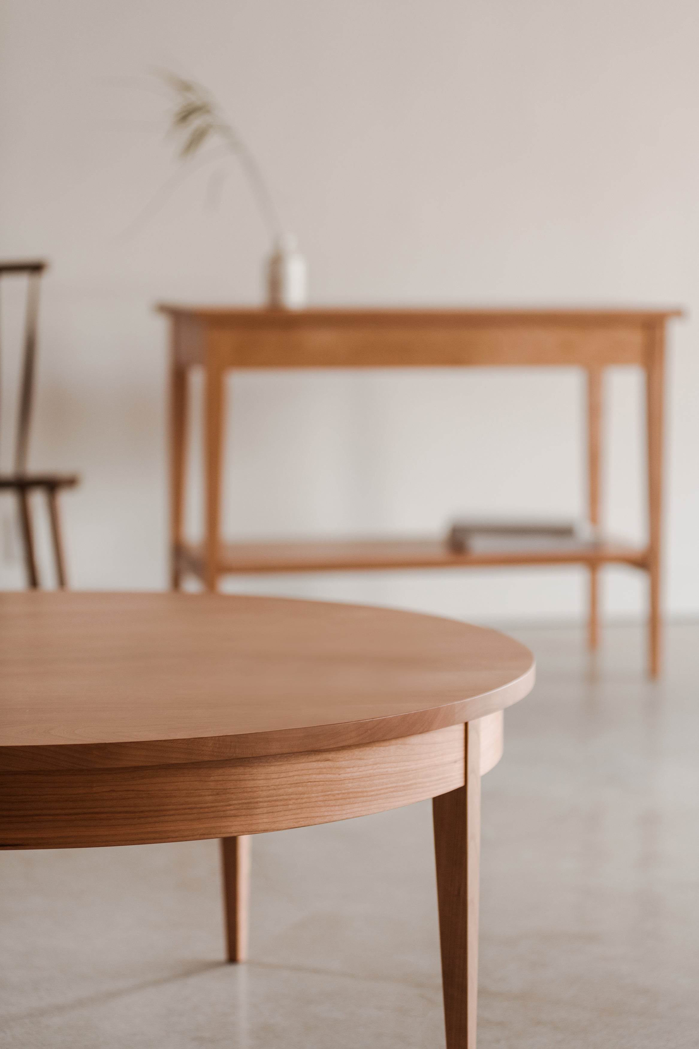 Shaker heirloom console table and round coffee table styled with vase, books and chair in the background