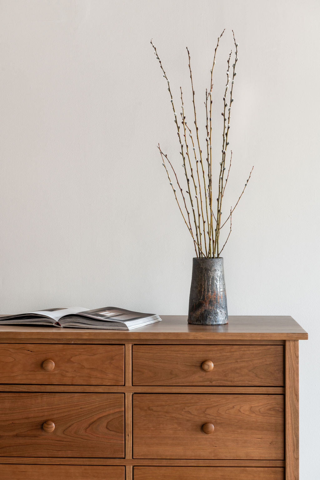 Modern bedroom with cherry wood dresser and hand thrown pottery 