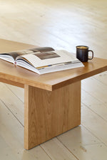 Casual wood coffee table with book and coffee on wood pine floors in bright room