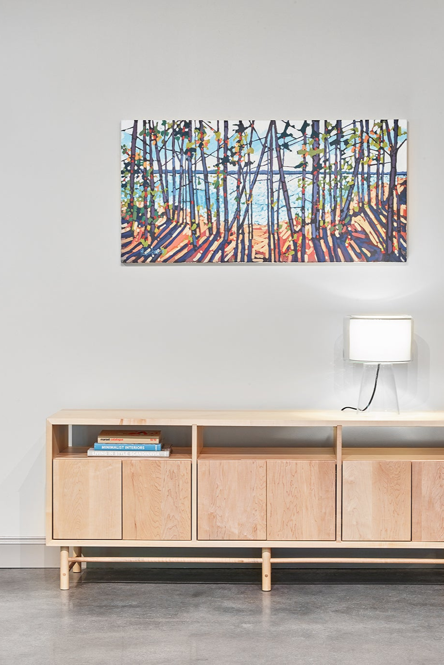 Industrial room with mid-century modern Navarend media case in solid maple with round legs and stretchers and an impressionism painting of trees