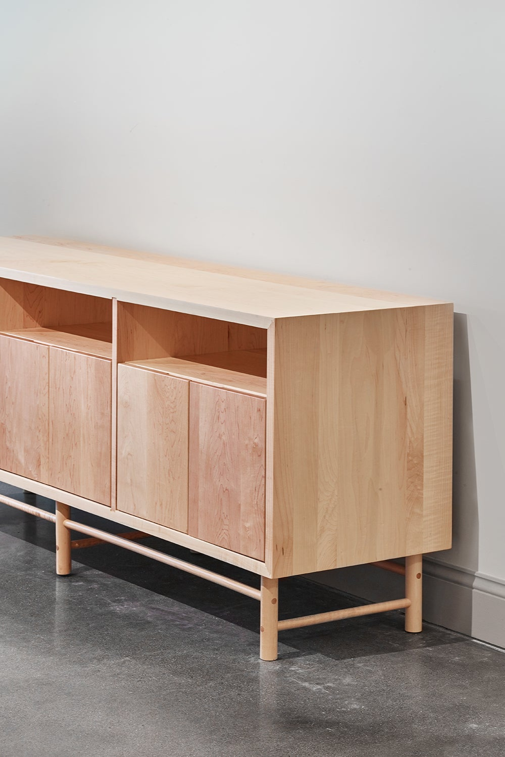 Industrial room with mid-century modern Navarend media case in solid maple wood with round legs and stretchers and six doors with storage space