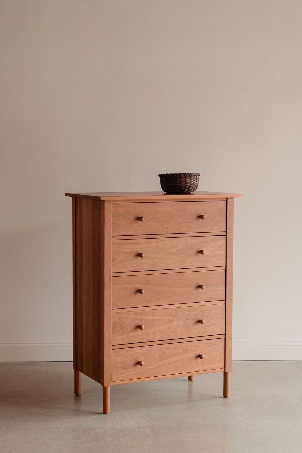 Wooden dresser with five drawers on a plain background