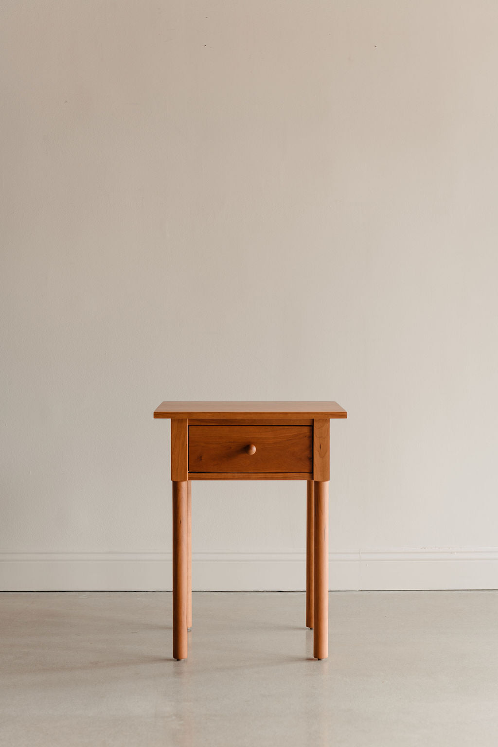 Modern interpretation of a classic Shaker style nightstand with one drawer and rounded legs, in solid cherry wood