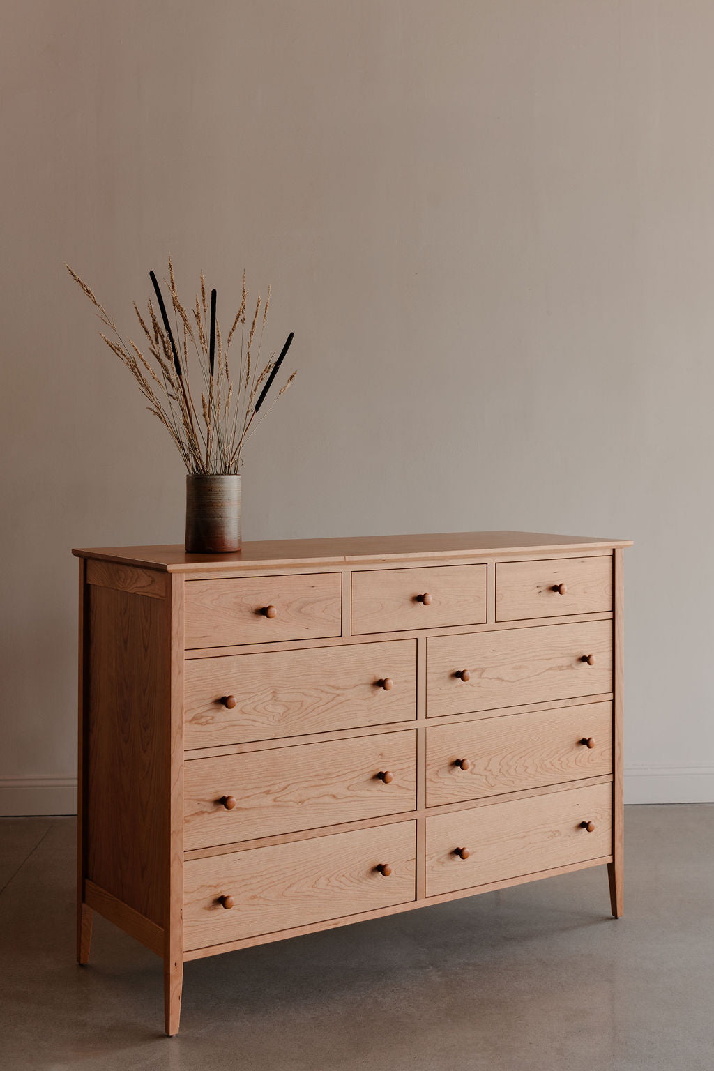 Wooden dresser with multiple drawers against a plain wall.