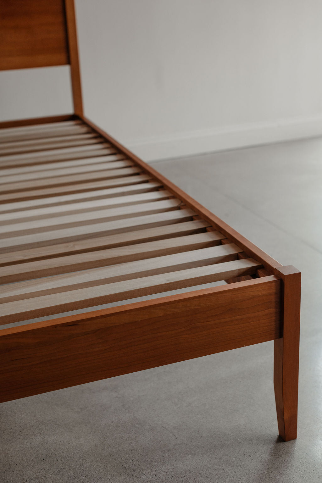 Wooden bed frame with slats on a plain background