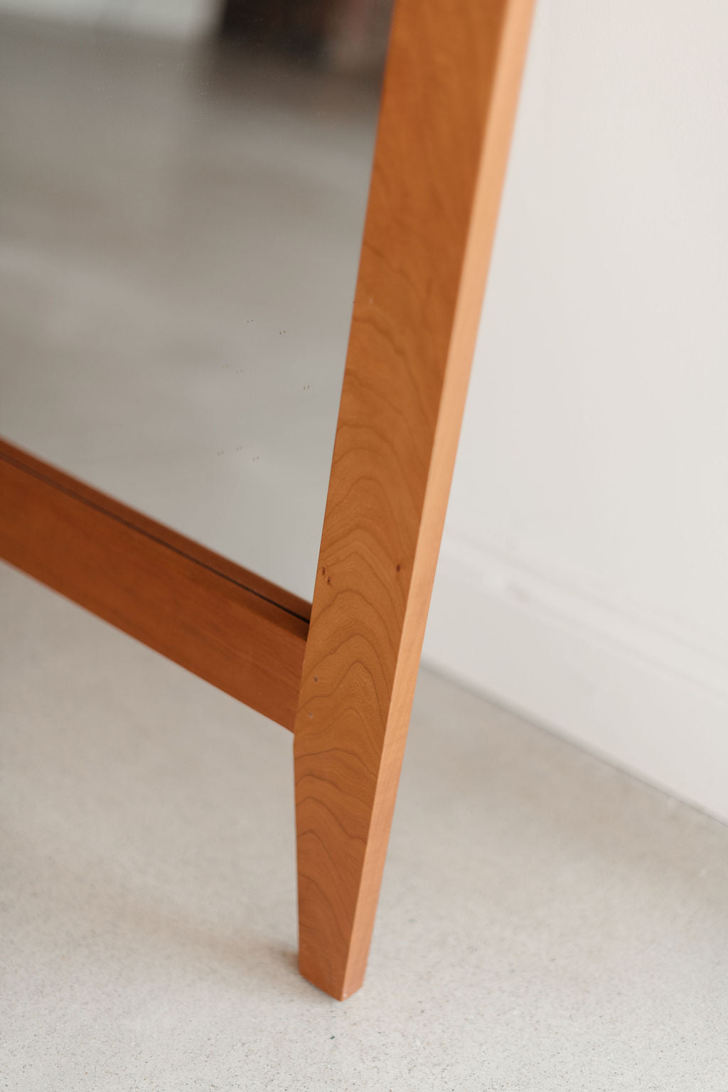 Close-up of a wooden mirror leg on a neutral background
