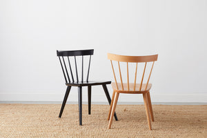 Two modern Windsor inspired spindle chairs, one painted black and one in white oak