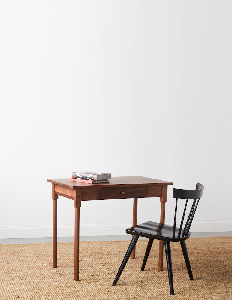 Small walnut MS1 desk with rounded legs and books on top paired with black modern windsor inspired spindle chair