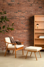 Reading nook with brick wall, cherry Nautilus Lounge Chair and Ottoman, Lubec bookcase and black Portable Dipping Lamp