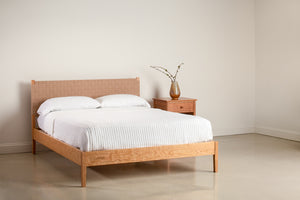 Shaker style bed with woven headboard with nightstand in cherry