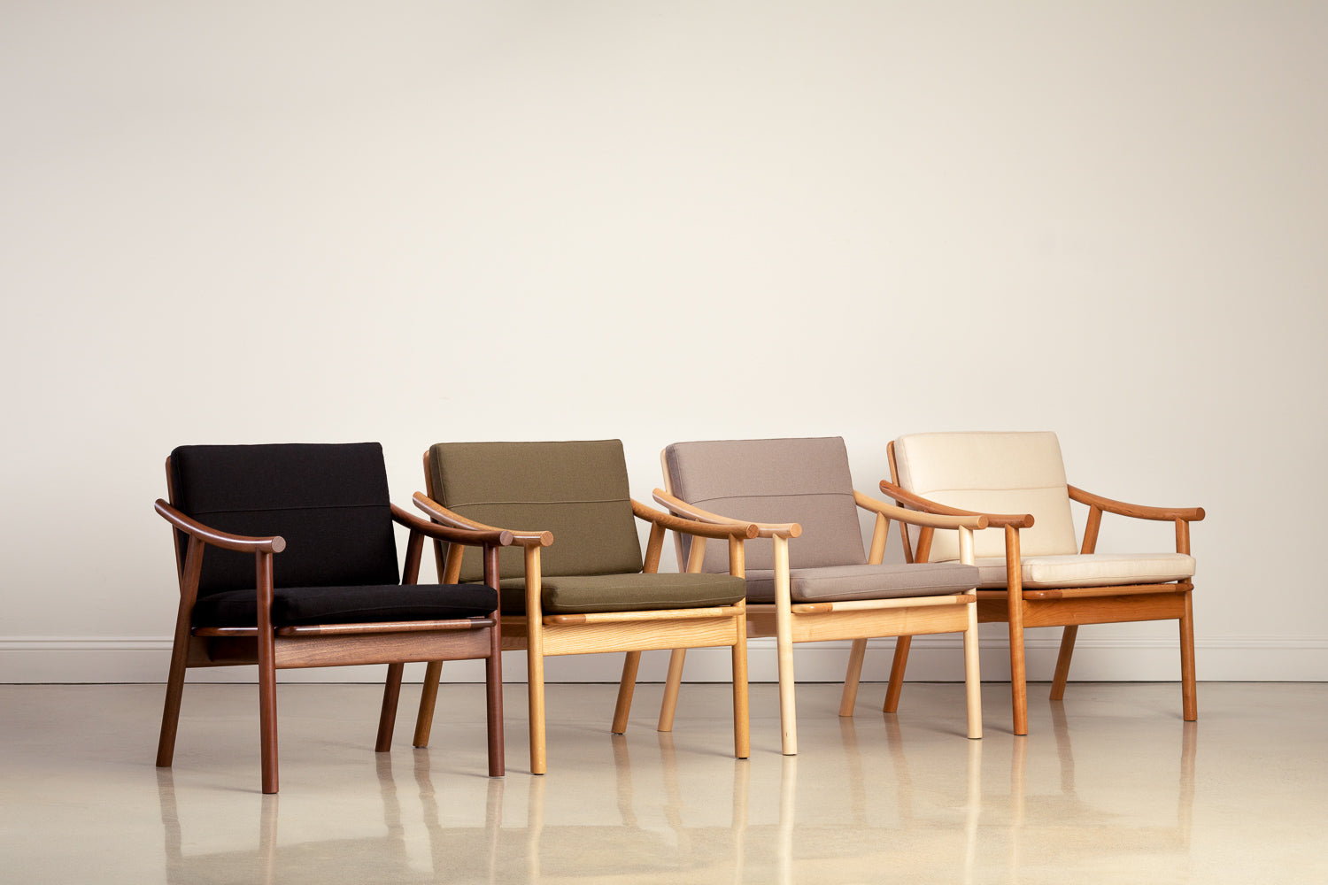 Four Scandinavian style lounge chairs in a row in a rainbow pattern with woods in walnut, oak, maple and cherry