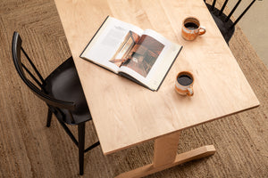 Coffee cups and an open book on the Acadia Breakfast Bar in maple with black counter stools