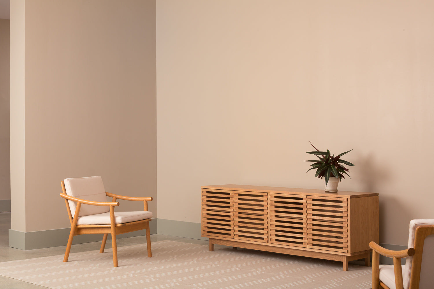 Modern minimalist living room with white oak Upland Media Stand and two Nautilis Loung Chairs for furniture, styled with plant and tan rug