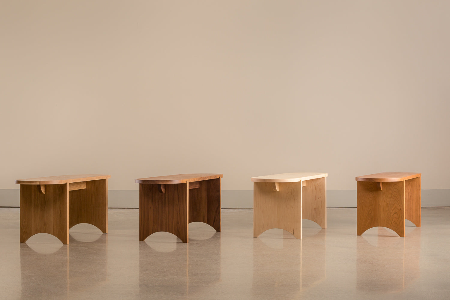 Four oval Portland Bench's lined up in different woods: white oak, walnut, maple and cherry