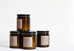 Stack of four candles in amber glass jars with black lids