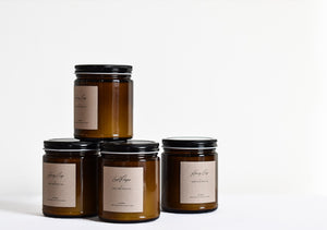 Stack of four candles in amber glass jars with black lids