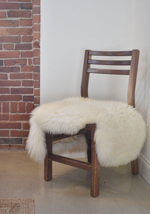 Solid walnut wood dining chair with white sheepskin throw on seat