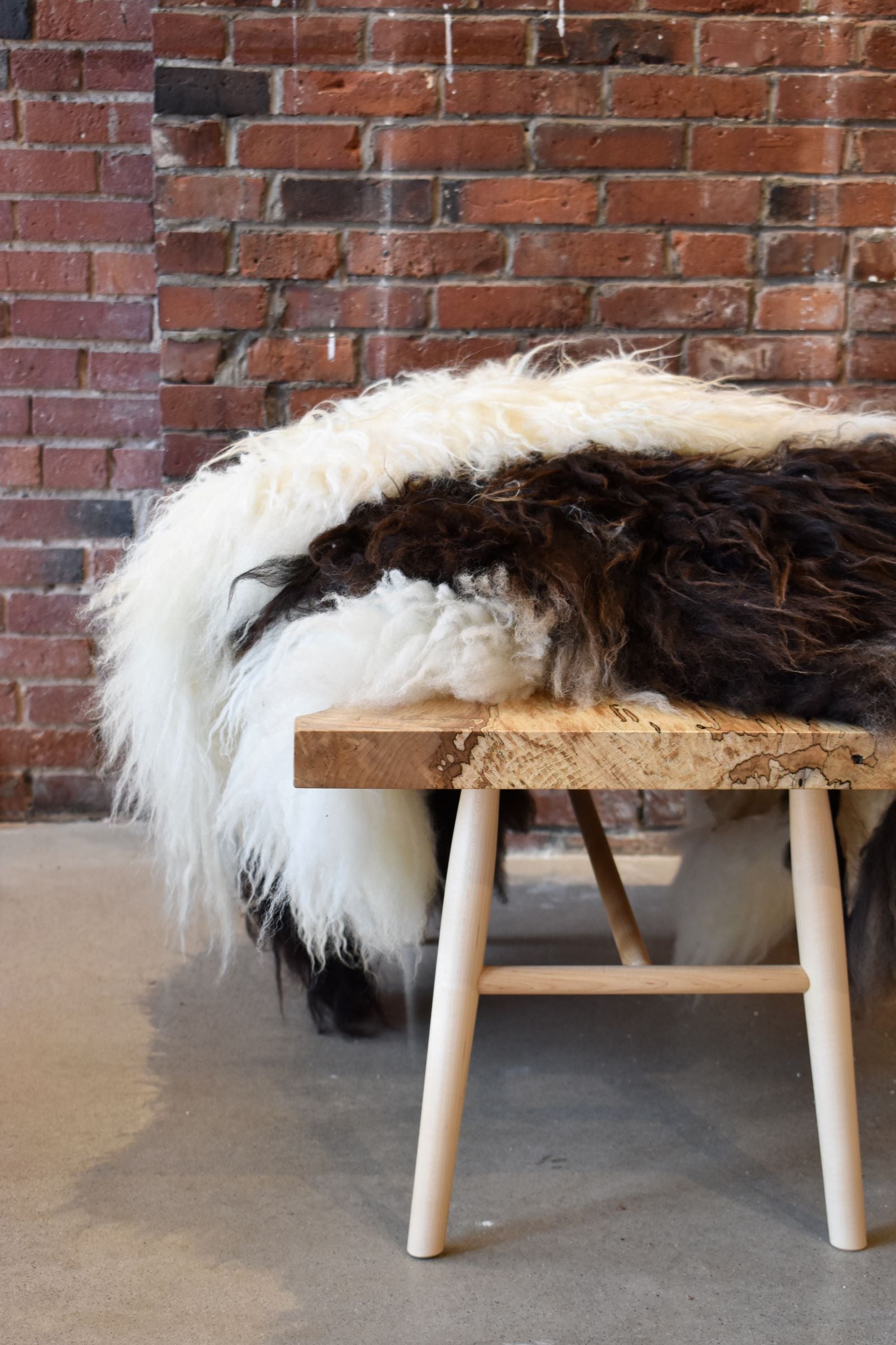 Solid wood bench with pile of white and brown sheepskin throws
