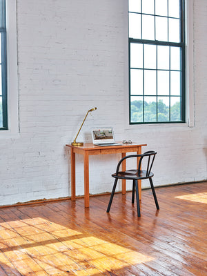 Office with painted brick walls furnished with small cherry Acadia desk and modern black bistro chair